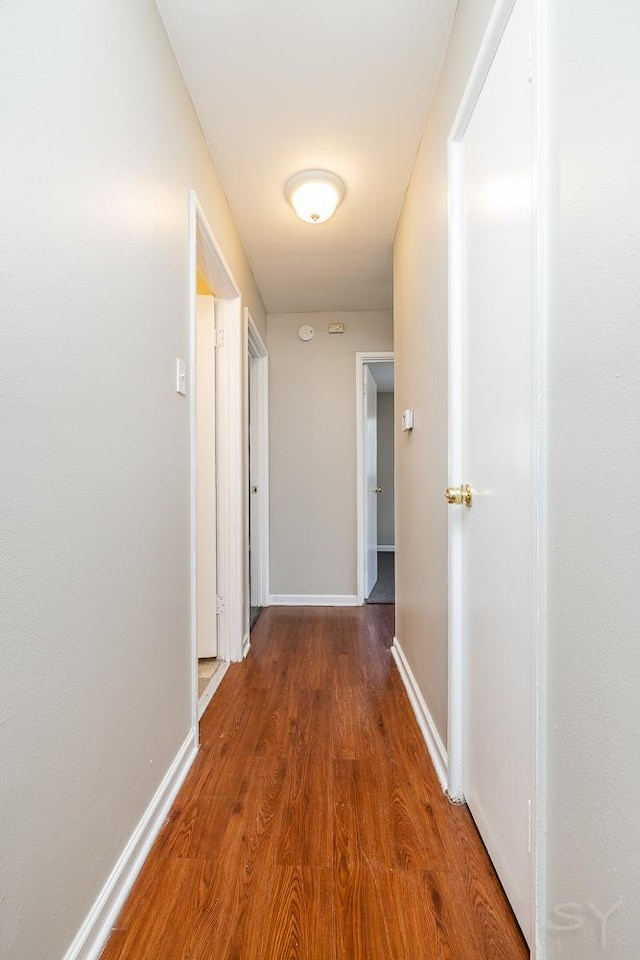 corridor featuring wood finished floors and baseboards