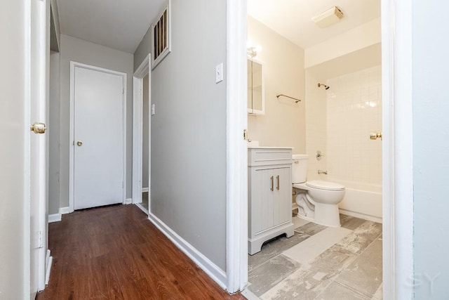 interior space with baseboards, shower / tub combination, vanity, and toilet