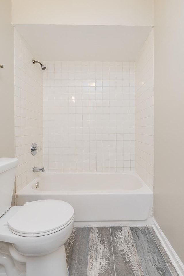 full bathroom featuring toilet, washtub / shower combination, baseboards, and wood finished floors