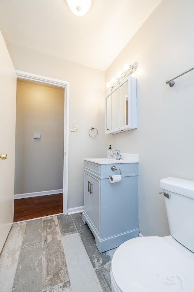 bathroom featuring toilet, baseboards, and vanity