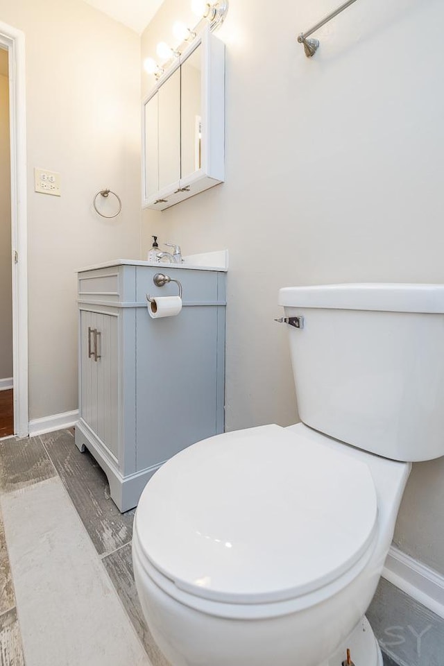 bathroom with baseboards, vanity, and toilet