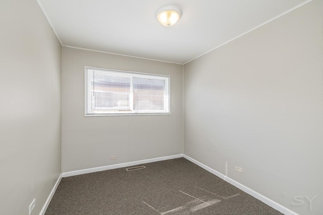 spare room featuring ornamental molding, visible vents, dark carpet, and baseboards