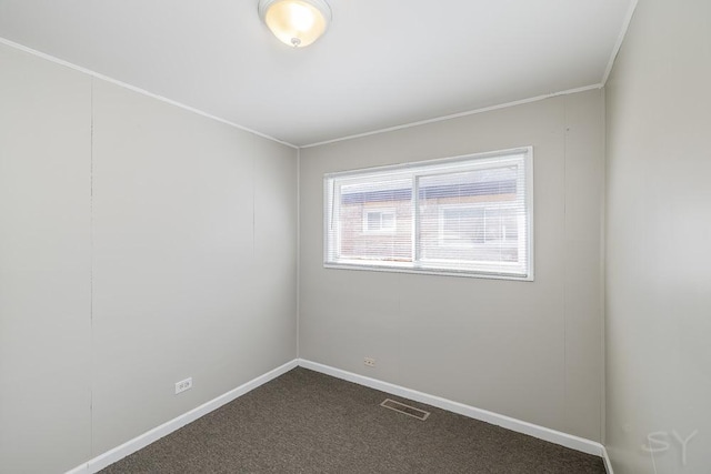 empty room featuring baseboards, visible vents, and dark carpet