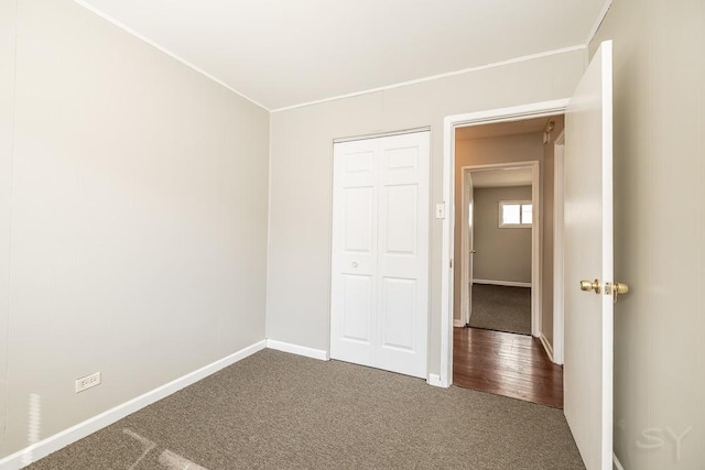 unfurnished bedroom with crown molding, a closet, carpet, and baseboards