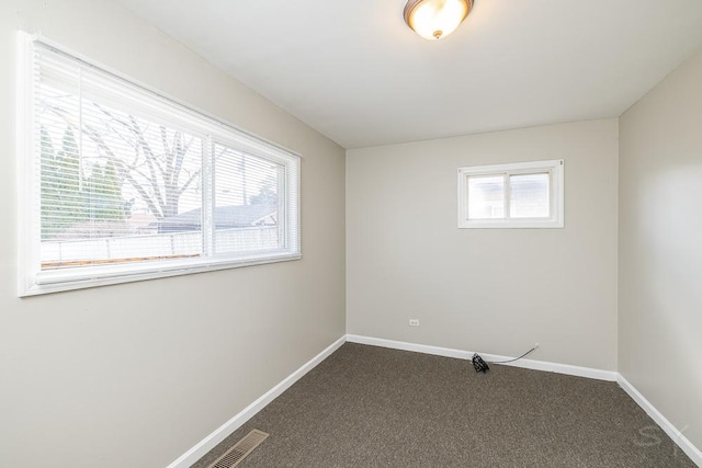 spare room featuring carpet, visible vents, and baseboards