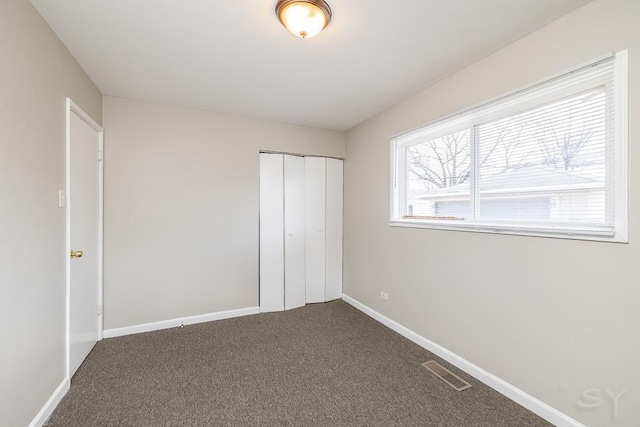 unfurnished bedroom with carpet floors, baseboards, visible vents, and a closet