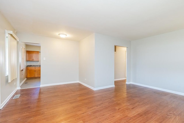 unfurnished room with light wood finished floors, baseboards, and visible vents