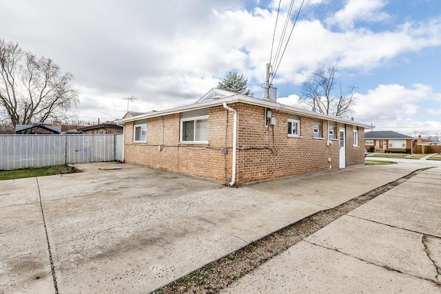 view of home's exterior featuring brick siding and fence