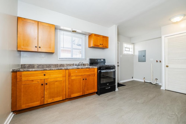 kitchen featuring brown cabinetry, black range with gas cooktop, dark stone counters, electric panel, and baseboards