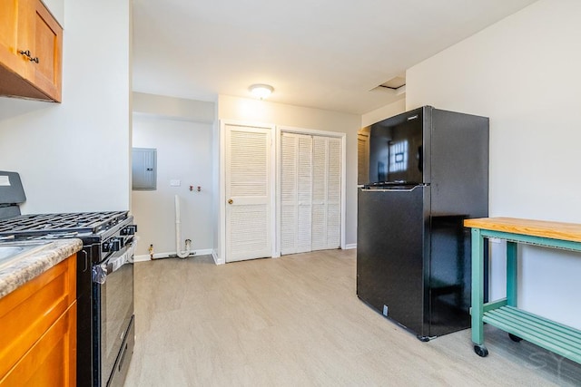 kitchen featuring light wood-style flooring, light countertops, electric panel, brown cabinets, and black appliances