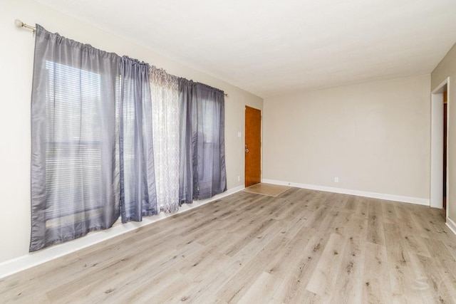 unfurnished room with light wood-style flooring and baseboards