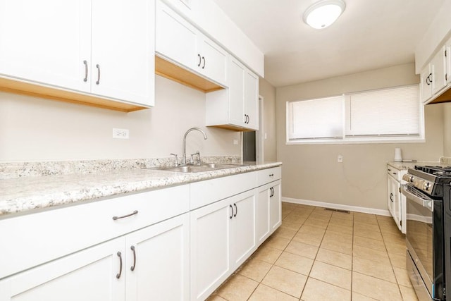 kitchen with stainless steel gas stove, light tile patterned floors, visible vents, white cabinets, and a sink