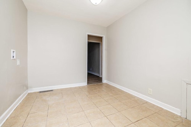 empty room with light tile patterned floors, visible vents, and baseboards