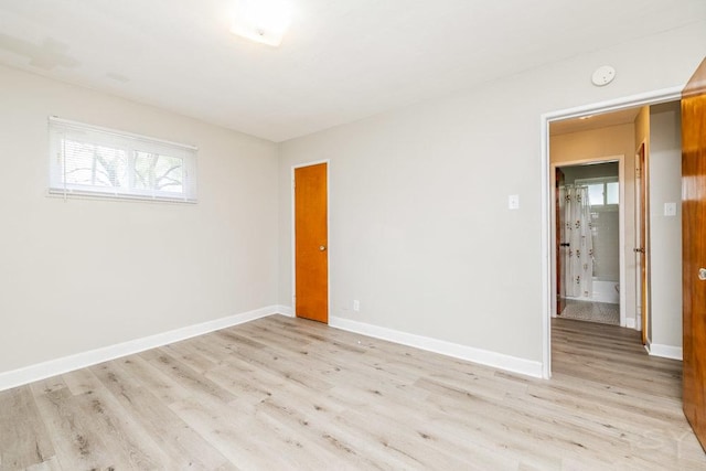 unfurnished room with light wood-type flooring and baseboards