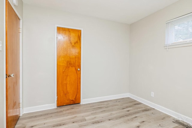 empty room featuring light wood-type flooring, visible vents, and baseboards