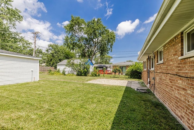 view of yard featuring a patio, an outdoor structure, and fence