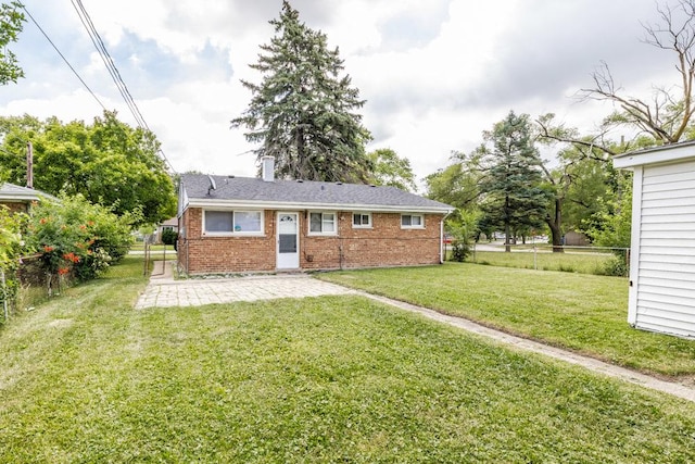 back of house with brick siding, a yard, a chimney, a patio, and a fenced backyard