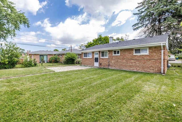 view of front of home featuring a front yard, a chimney, and brick siding