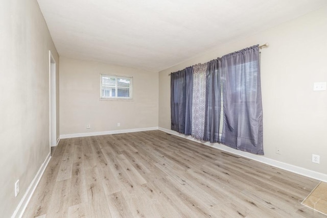 unfurnished room with baseboards and light wood finished floors