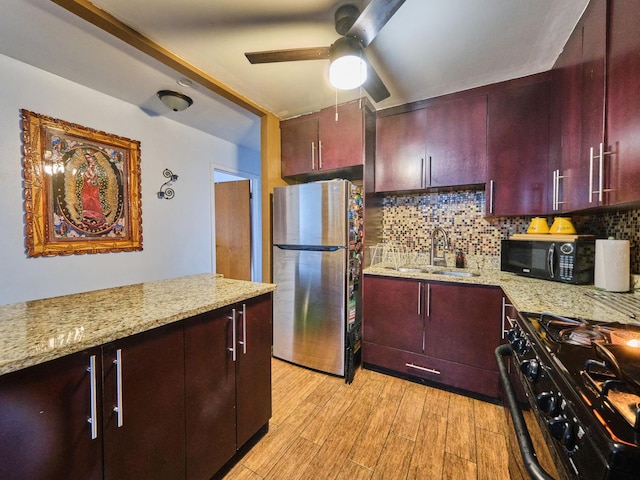 kitchen featuring light stone countertops, backsplash, light hardwood / wood-style floors, and black appliances