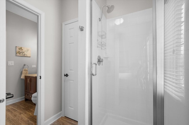 bathroom with hardwood / wood-style flooring, an enclosed shower, and toilet