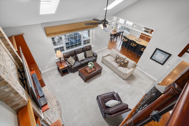 living room featuring a skylight, high vaulted ceiling, carpet flooring, and ceiling fan