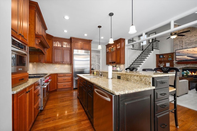 kitchen featuring sink, a breakfast bar, high end appliances, pendant lighting, and an island with sink