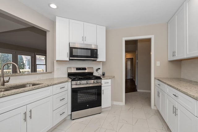 kitchen with white cabinetry, sink, light stone counters, and stainless steel appliances