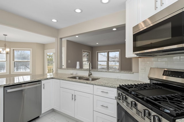 kitchen featuring sink, white cabinetry, appliances with stainless steel finishes, a wealth of natural light, and light stone countertops