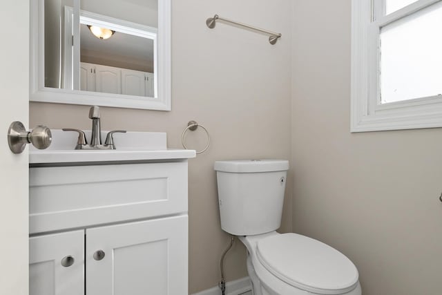 bathroom with baseboards, vanity, and toilet