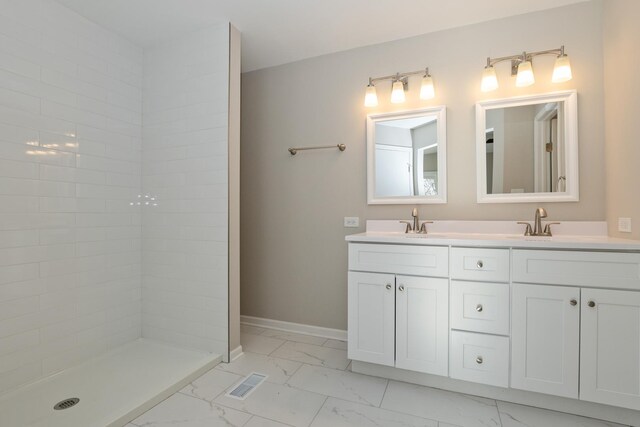 bathroom with marble finish floor, double vanity, visible vents, a sink, and baseboards