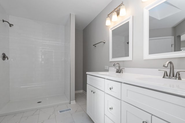 bathroom featuring marble finish floor, double vanity, a sink, and visible vents