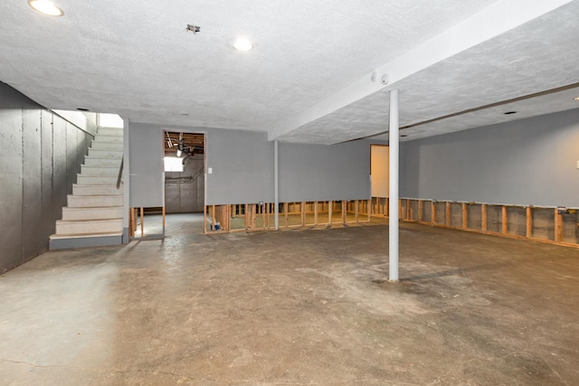 below grade area with a textured ceiling and stairway