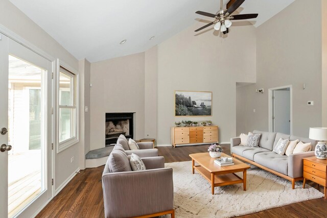 living area with a fireplace with raised hearth, baseboards, and dark wood finished floors