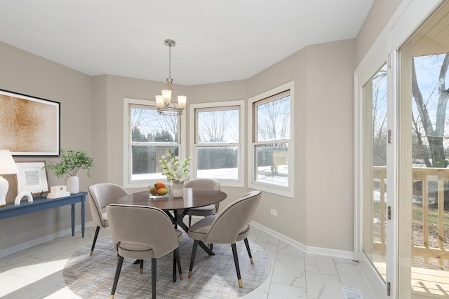 dining space featuring marble finish floor, an inviting chandelier, and baseboards