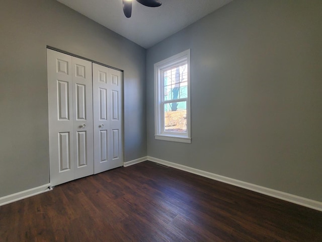 unfurnished bedroom with a ceiling fan, a closet, baseboards, and dark wood-type flooring