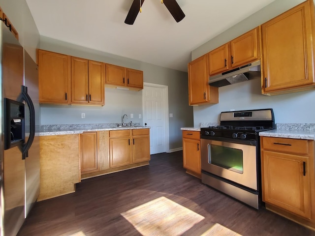 kitchen with dark wood finished floors, a ceiling fan, appliances with stainless steel finishes, under cabinet range hood, and a sink