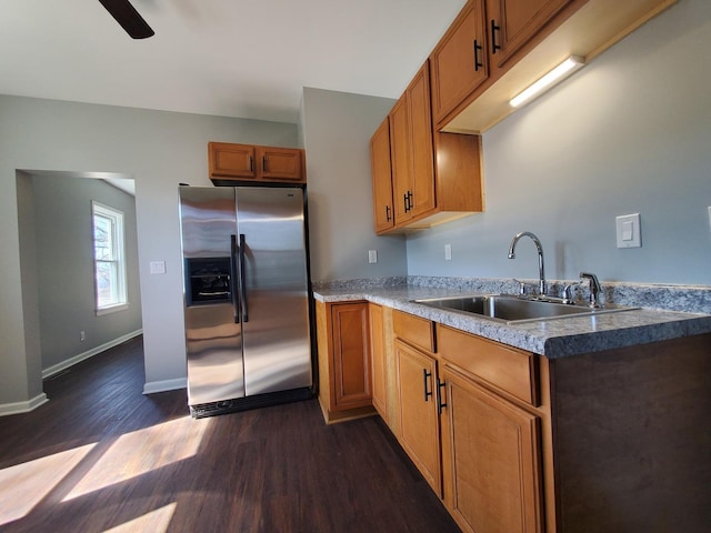 kitchen featuring a sink, dark wood finished floors, baseboards, brown cabinets, and stainless steel fridge