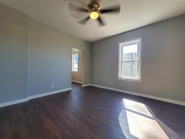 unfurnished room featuring dark wood finished floors, baseboards, and ceiling fan