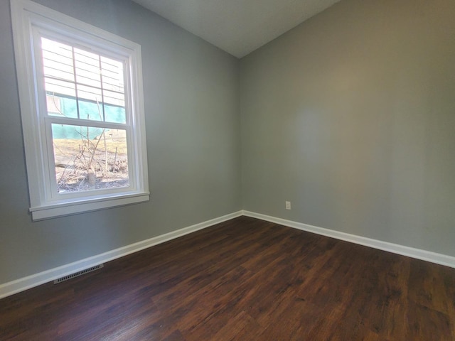 unfurnished room featuring dark wood-style floors, baseboards, and visible vents