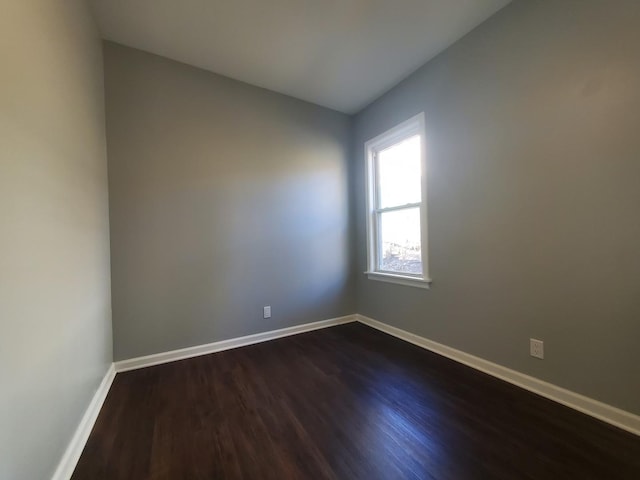 unfurnished room with dark wood-style flooring and baseboards