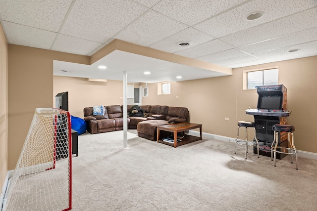 carpeted living area featuring a drop ceiling, visible vents, and baseboards