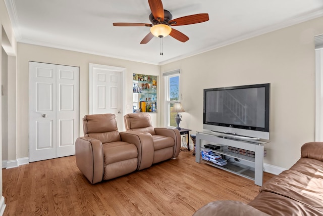 living area with ornamental molding, light wood-type flooring, ceiling fan, and baseboards