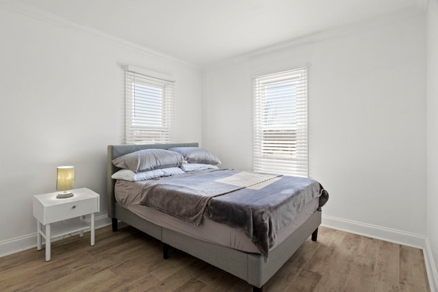 bedroom with multiple windows, ornamental molding, and wood finished floors