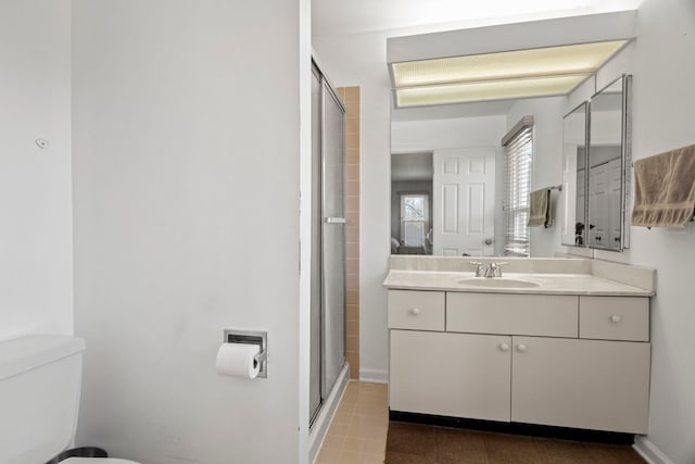 bathroom with baseboards, a shower stall, toilet, and vanity