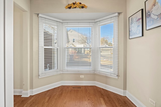 unfurnished dining area with visible vents, baseboards, and wood finished floors