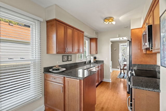 kitchen featuring stainless steel appliances, brown cabinets, a sink, and light wood finished floors