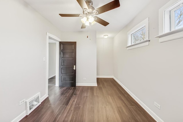 unfurnished bedroom featuring ceiling fan, dark hardwood / wood-style floors, and multiple windows