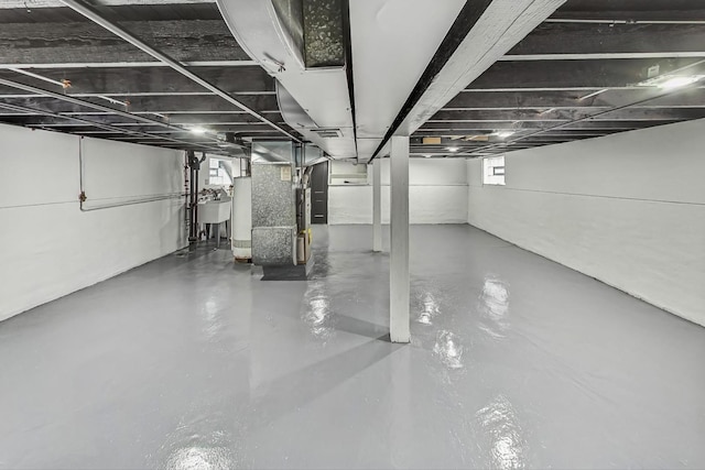 basement featuring gas water heater, sink, and heating unit