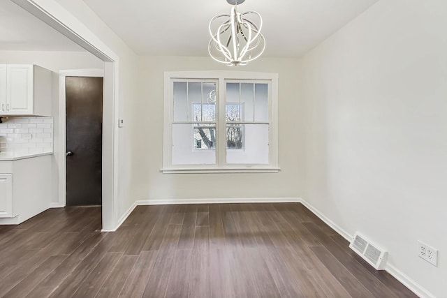 unfurnished dining area with a chandelier and dark hardwood / wood-style flooring